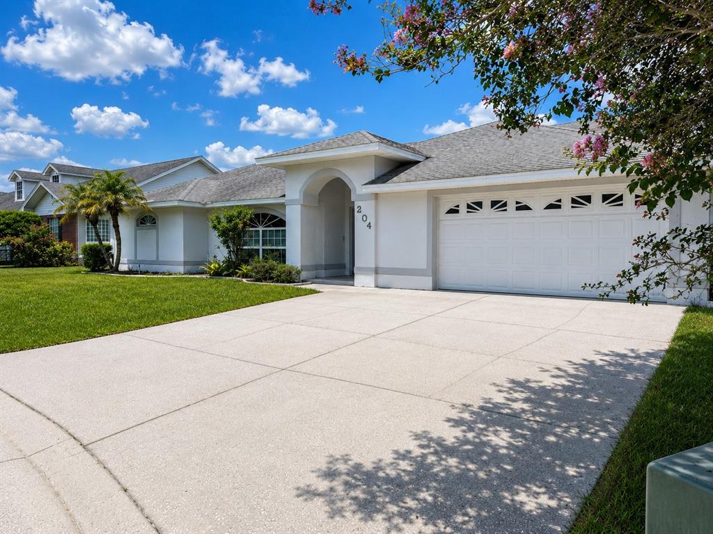 A single-story house with a white exterior, a two-car garage, and a concrete driveway — 204 LAKE MARIAM COURT, WINTER HAVEN, FL