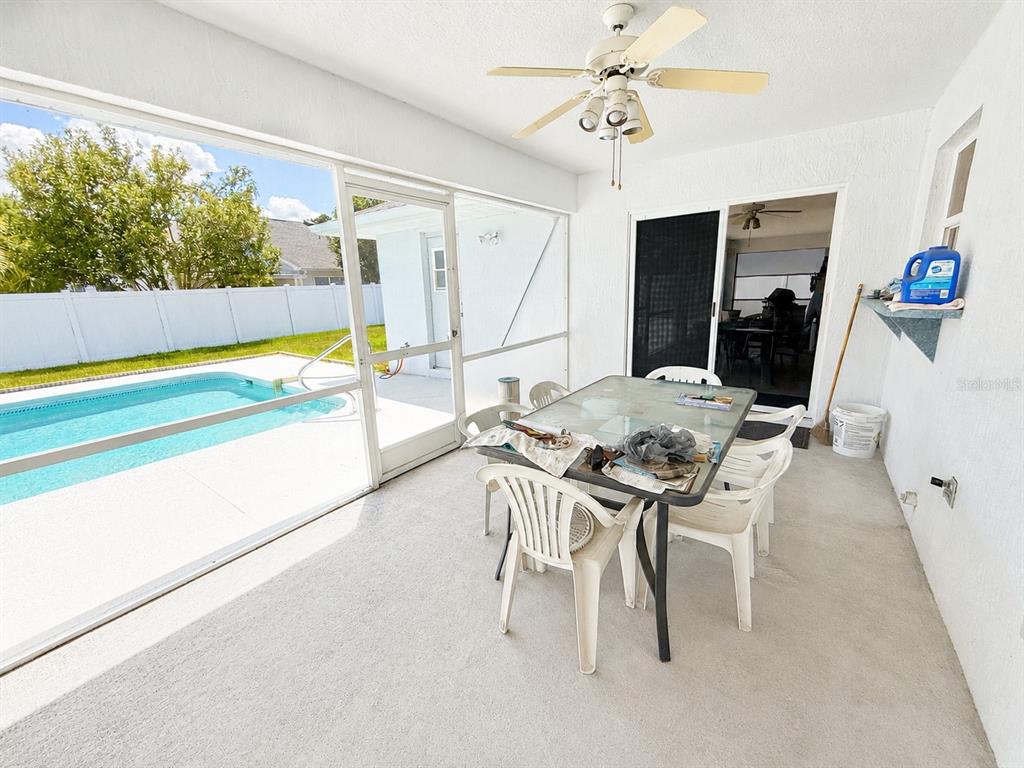 A screened-in patio features a dining set, ceiling fan, and a view of a swimming pool — 204 LAKE MARIAM COURT, WINTER HAVEN, FL