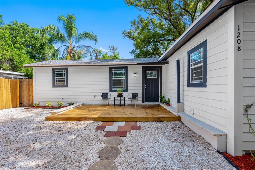 A single-story house with light siding, a gravel driveway, and a wooden fence — 1208 E CHILKOOT AVENUE, TAMPA, FL