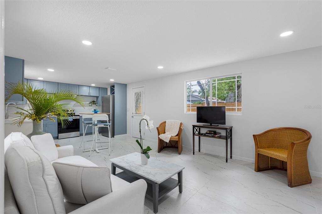 A white house exterior features a wooden deck, two chairs, and a small table — 1208 E CHILKOOT AVENUE, TAMPA, FL