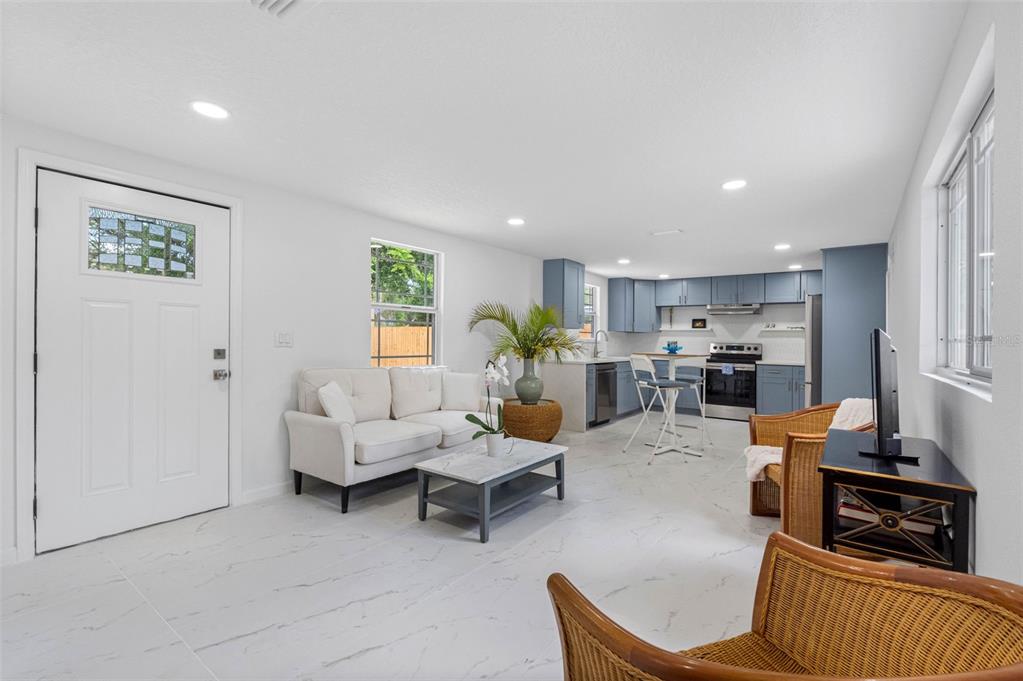 A white house exterior features a wooden deck, dark window trim, and a gravel yard — 1208 E CHILKOOT AVENUE, TAMPA, FL