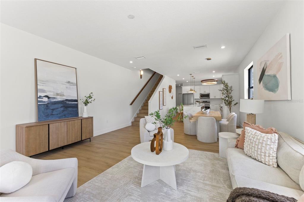 An open-concept living and dining area features light wood floors, white walls, and modern furniture — 6216 64TH WAY N, PINELLAS PARK, FL