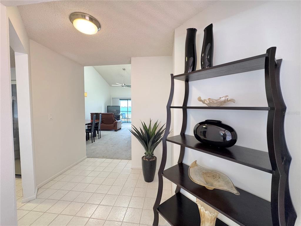 A tiled entryway leads to a living area featuring a dark wooden bookshelf and decor — 715 MAGNOLIA PLACE UNIT 715, WINTER HAVEN, FL