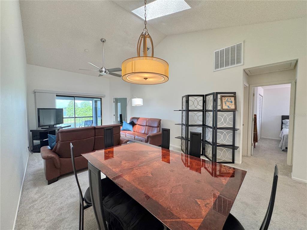 A dining area with a glossy table and a living room with brown leather furniture — 715 MAGNOLIA PLACE UNIT 715, WINTER HAVEN, FL