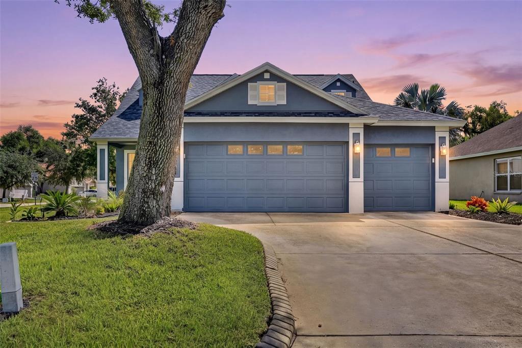 A blue house with a three-car garage and a large tree in the front yard — 4007 34TH STREET E, BRADENTON, FL
