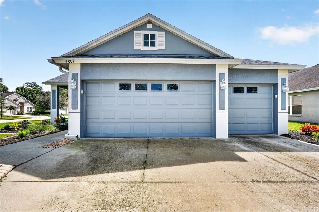 A blue house exterior features a three-car garage and a small attic window — 4007 34TH STREET E, BRADENTON, FL