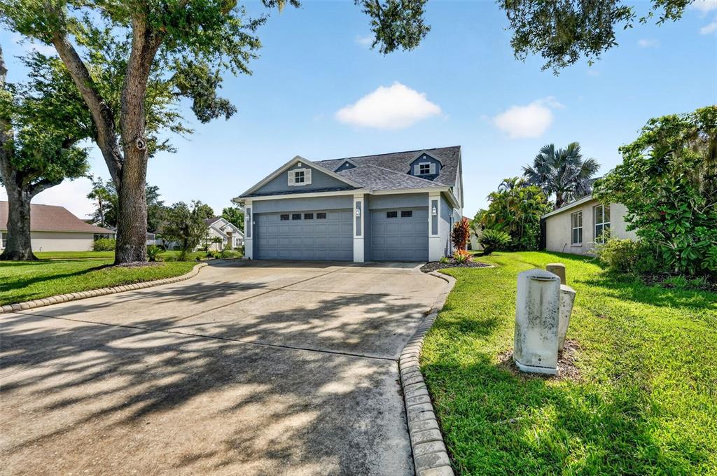 A blue house with a three-car garage and a concrete driveway under a blue sky — 4007 34TH STREET E, BRADENTON, FL
