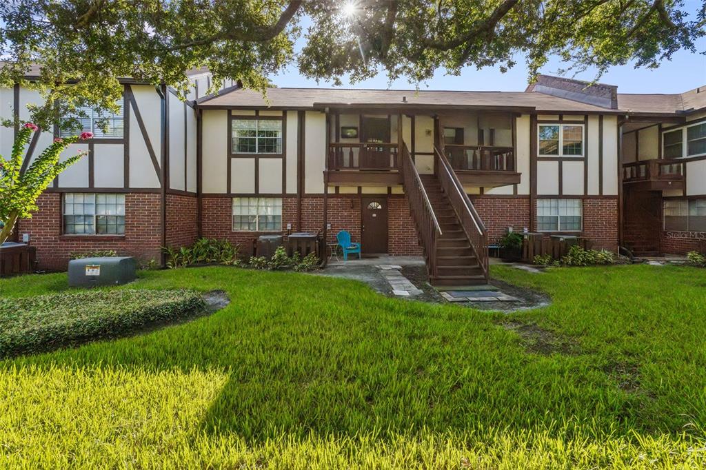 A two-story apartment building features brick and stucco siding with an exterior wooden staircase — 5311 HANSEL AVENUE UNIT D14, ORLANDO, FL