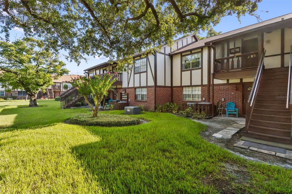 Exterior view of a two-story apartment building with brick siding, wooden stairs, and grassy lawn — 5311 HANSEL AVENUE UNIT D14, ORLANDO, FL