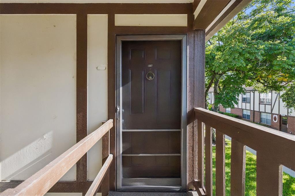 A dark brown front door with a screen door is situated on a wooden balcony — 5311 HANSEL AVENUE UNIT D14, ORLANDO, FL