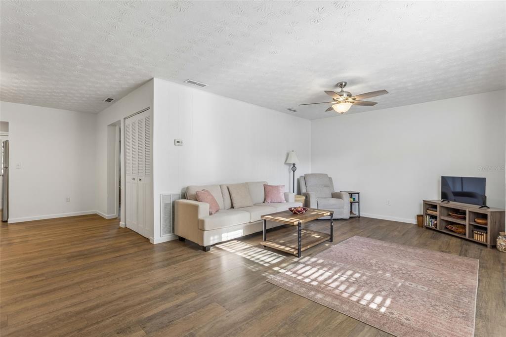 A living room features light wood-look flooring, a beige sofa, a recliner, and a television stand — 5311 HANSEL AVENUE UNIT D14, ORLANDO, FL