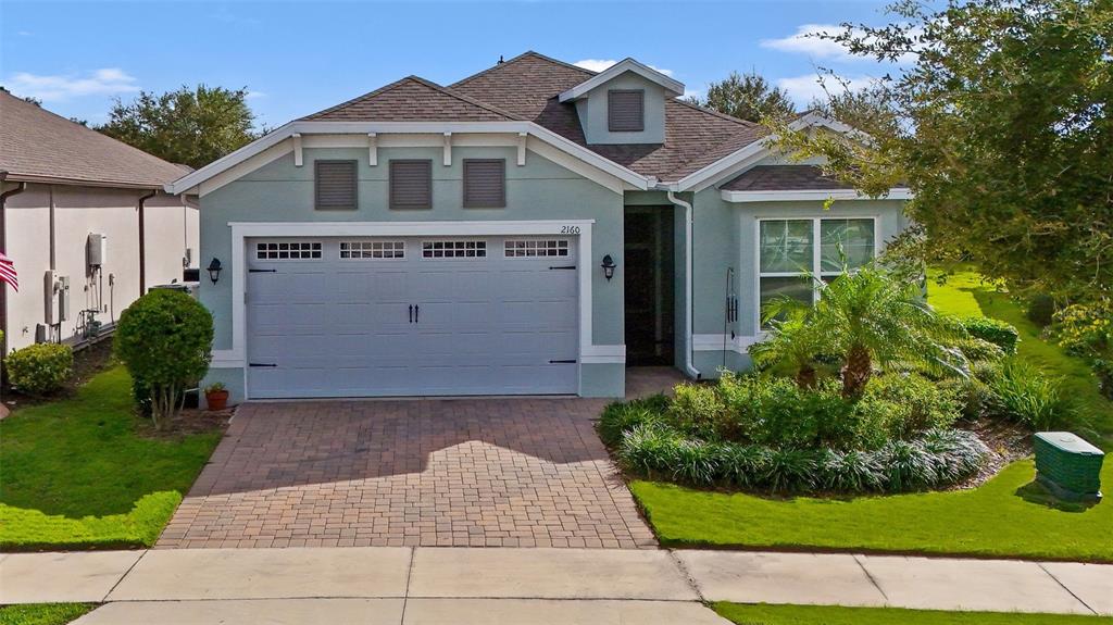 A light blue single-story house features a two-car garage and a paved driveway — 2160 ANTILLES CLUB DRIVE, KISSIMMEE, FL