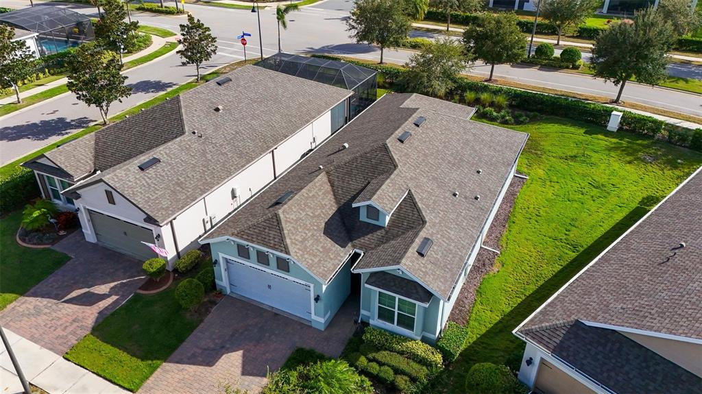 An aerial view shows the roofs and front driveways of three suburban houses with green lawns — 2160 ANTILLES CLUB DRIVE, KISSIMMEE, FL