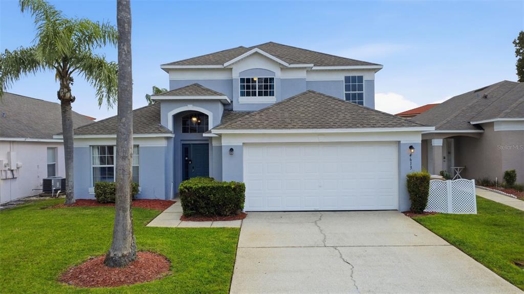 A two-story blue house with a white garage door and a palm tree in front — 4613 FORMBY COURT, KISSIMMEE, FL