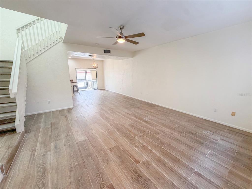 An open living area features wood-look tile flooring, a ceiling fan, and a staircase — 3460 COUNTRYSIDE BOULEVARD UNIT 60, CLEARWATER, FL