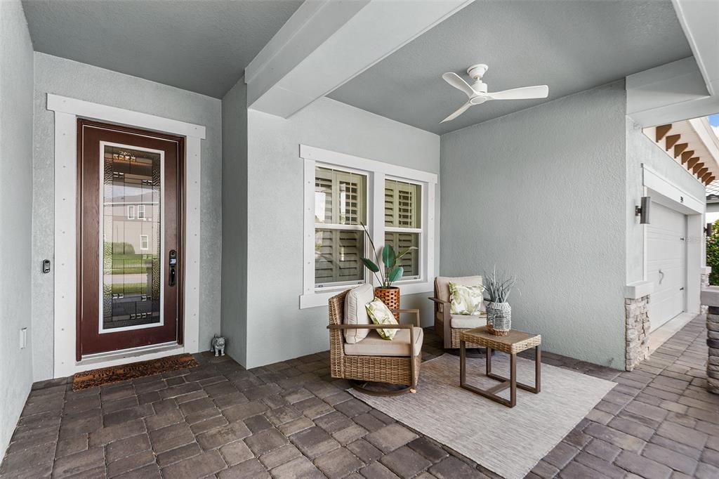 A covered front porch features a brown door, two wicker chairs, and a ceiling fan — 3994 WOODLAND RETREAT BOULEVARD, NEW PORT RICHEY, FL