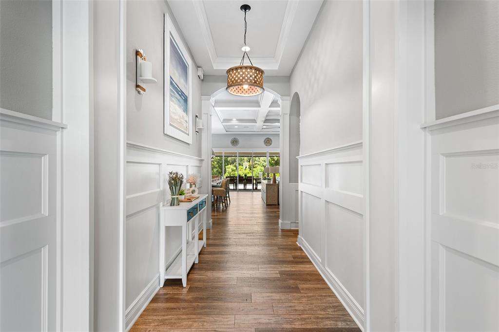 A bright hallway with white wainscoting, wood flooring, and a decorative pendant light fixture — 3994 WOODLAND RETREAT BOULEVARD, NEW PORT RICHEY, FL