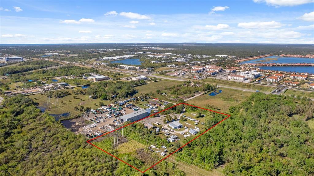 An aerial view shows a fenced property with several buildings surrounded by trees and vegetation — 3530 LAUREL ROAD E UNIT A, NORTH VENICE, FL