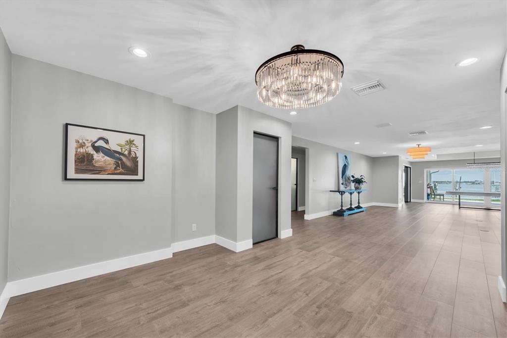 A modern kitchen features a large dark island, light grey cabinetry, and a wine rack wall — 303 N BATH CLUB BOULEVARD N, NORTH REDINGTON BEACH, FL