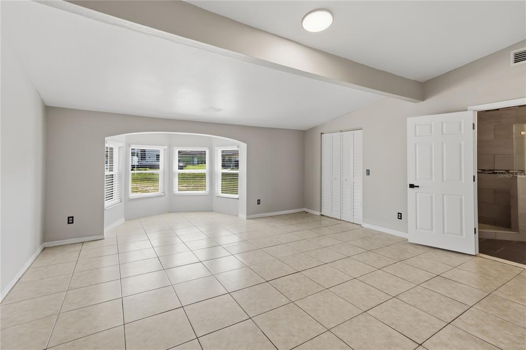 A spacious room with light tile flooring, a bay window, and a white closet door — 4870 LAKE CECILE DRIVE, KISSIMMEE, FL
