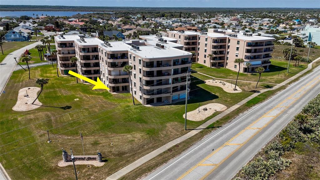 An aerial view shows a multi-story apartment complex with a yellow arrow pointing toward ground-level units — 3360 OCEAN SHORE BOULEVARD UNIT 103, ORMOND BEACH, FL