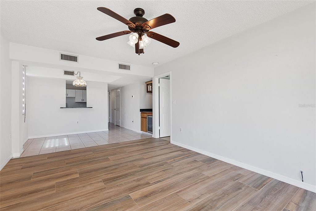 A living room with wood-look flooring, a ceiling fan, and sliding glass doors to outdoors — 3360 OCEAN SHORE BOULEVARD UNIT 103, ORMOND BEACH, FL