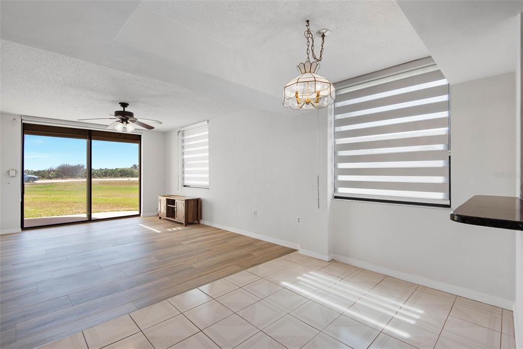 A living room features wood-look flooring, a ceiling fan, and a sliding glass door exterior view — 3360 OCEAN SHORE BOULEVARD UNIT 103, ORMOND BEACH, FL