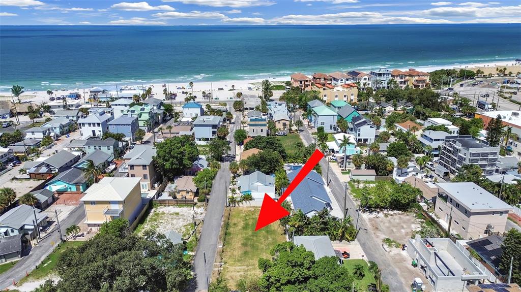 An aerial view shows a vacant rectangular lot surrounded by houses near the ocean — 140 92ND AVENUE, TREASURE ISLAND, FL