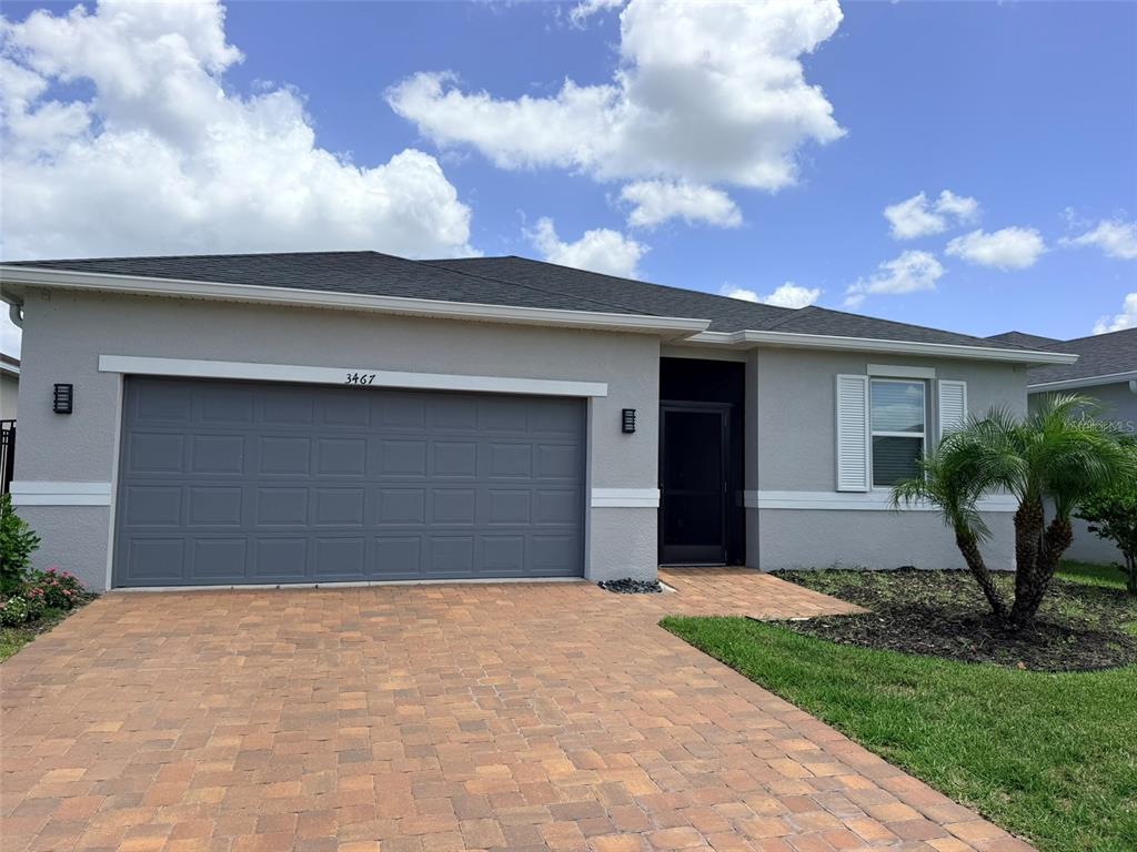 A single-story house with a gray garage, a paved driveway, and a small palm tree — 3467 74TH AVENUE CIRCLE E, SARASOTA, FL
