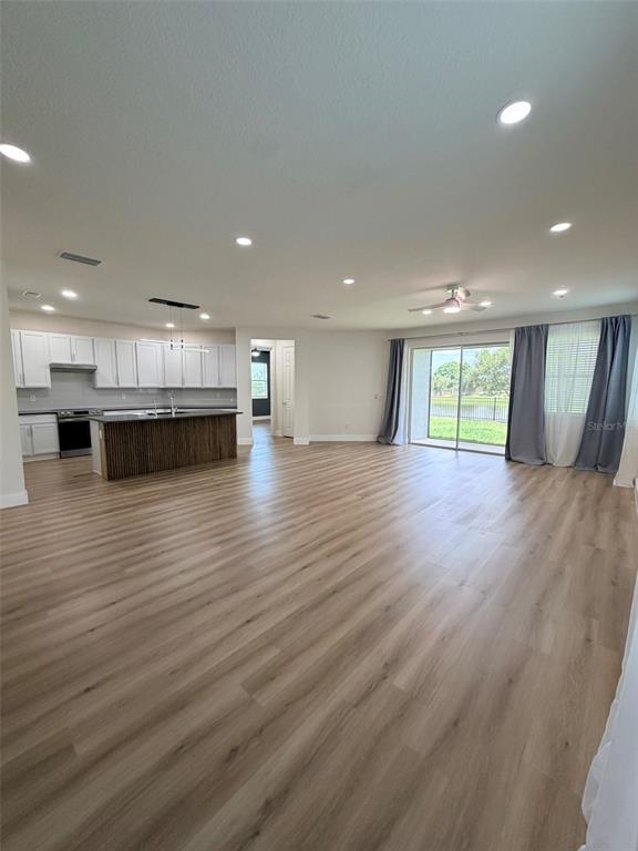 An open-concept kitchen and living area features light wood-look flooring and a sliding glass door — 3467 74TH AVENUE CIRCLE E, SARASOTA, FL