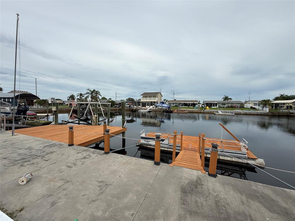 A concrete patio overlooks a canal with two wooden boat docks and several moored boats — 12739 3RD ISLE, HUDSON, FL