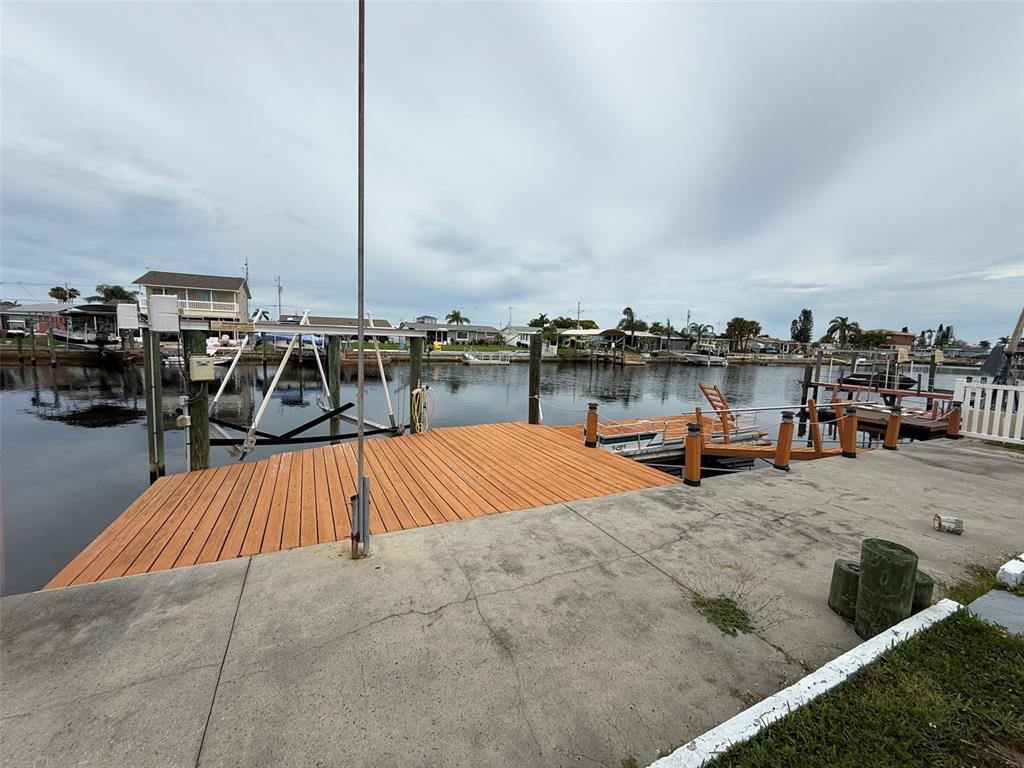 A wooden dock extends from a concrete patio into a canal with boat lifts — 12739 3RD ISLE, HUDSON, FL