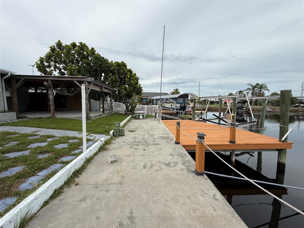 A concrete walkway leads to a wooden boat dock along a canal — 12739 3RD ISLE, HUDSON, FL