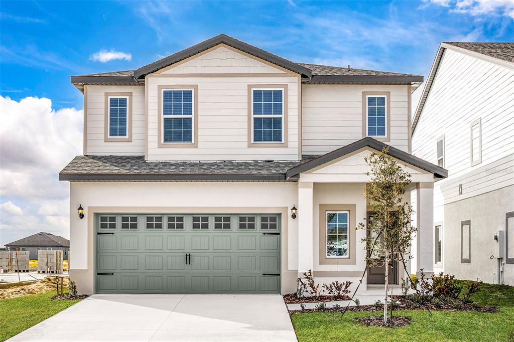 A two-story house with a sage green garage door, light siding, and a covered entryway — 3808 CORSICAN PLACE, LAKE ALFRED, FL