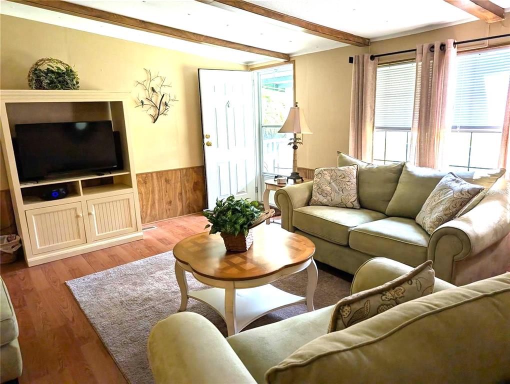 A living room features a light-colored entertainment center, a sofa, and a round coffee table — 56314 BLUE CREEK ROAD, ASTOR, FL
