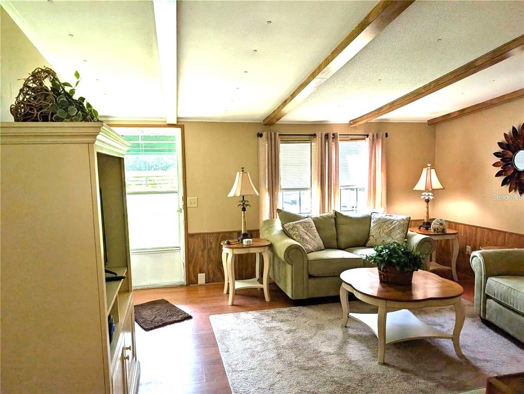 A living room features wood-paneled walls, a light-colored sofa, and a wooden coffee table — 56314 BLUE CREEK ROAD, ASTOR, FL