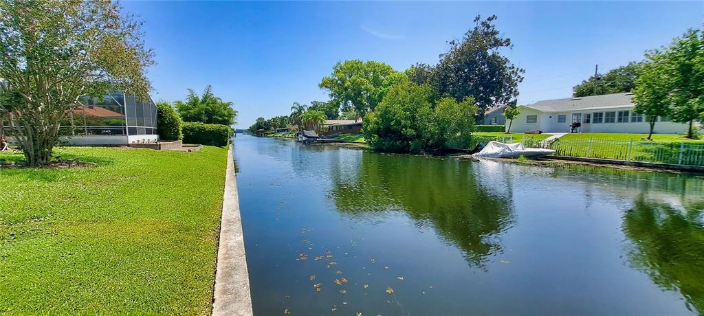 A view of a backyard canal with a lawn, patio, and surrounding residential houses — 2400 LAUDERDALE COURT, ORLANDO, FL