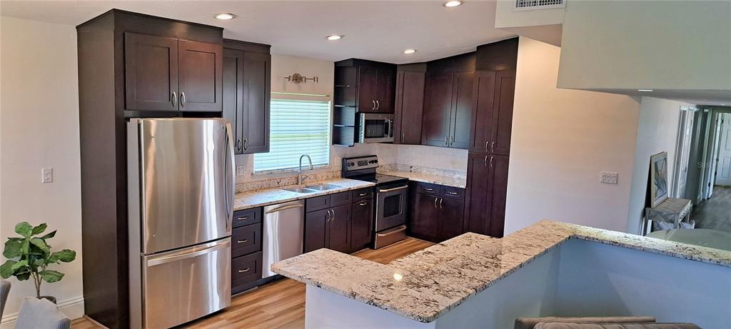 A bedroom with a vaulted ceiling, wood-look flooring, a large area rug, and pool access — 2400 LAUDERDALE COURT, ORLANDO, FL