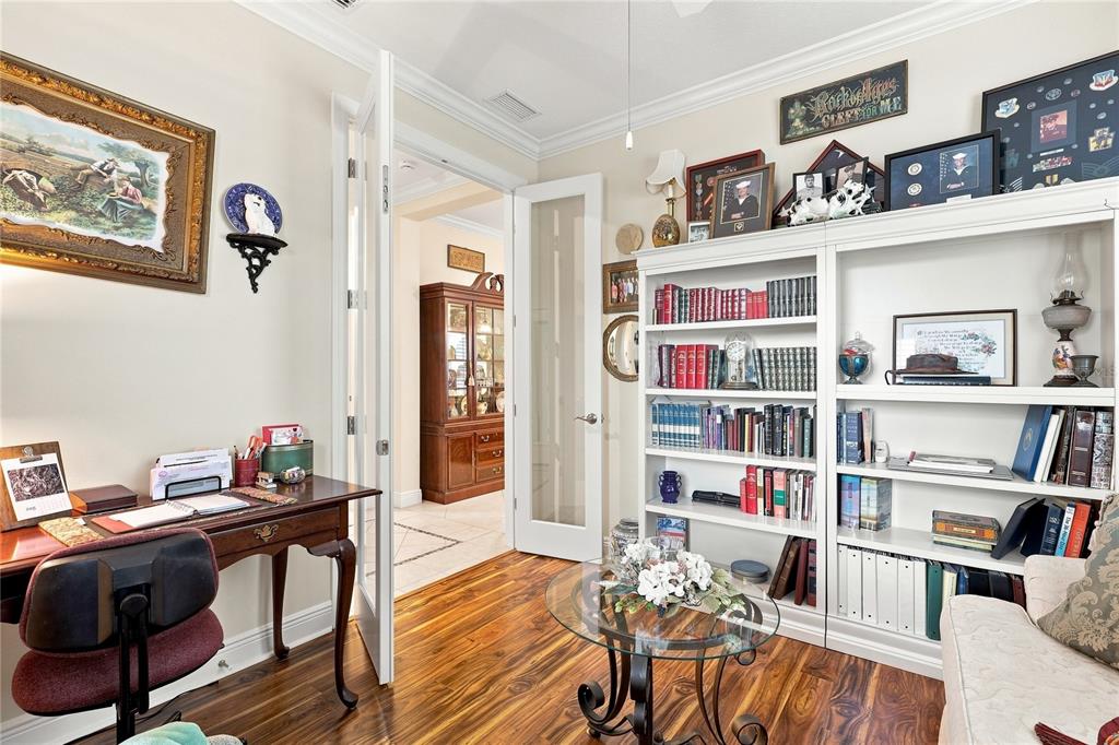 A home office features a wooden desk, a white bookshelf, and a glass-topped coffee table — 7201 VISTA BELLA DRIVE, BRADENTON, FL