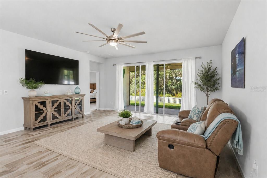 A living room with a brown leather sofa, wood coffee table, and sliding glass patio doors — 12943 SATIN LILY DRIVE, RIVERVIEW, FL