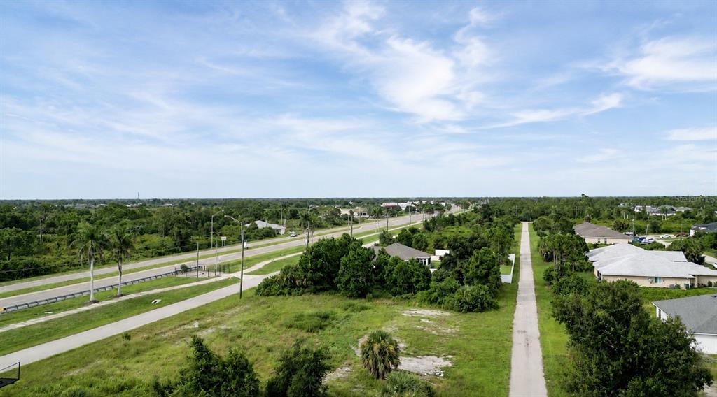 An aerial view shows a vacant grassy lot adjacent to a road and residential houses — 8540 & 8546 & 8552 WILTSHIRE DRIVE, PORT CHARLOTTE, FL