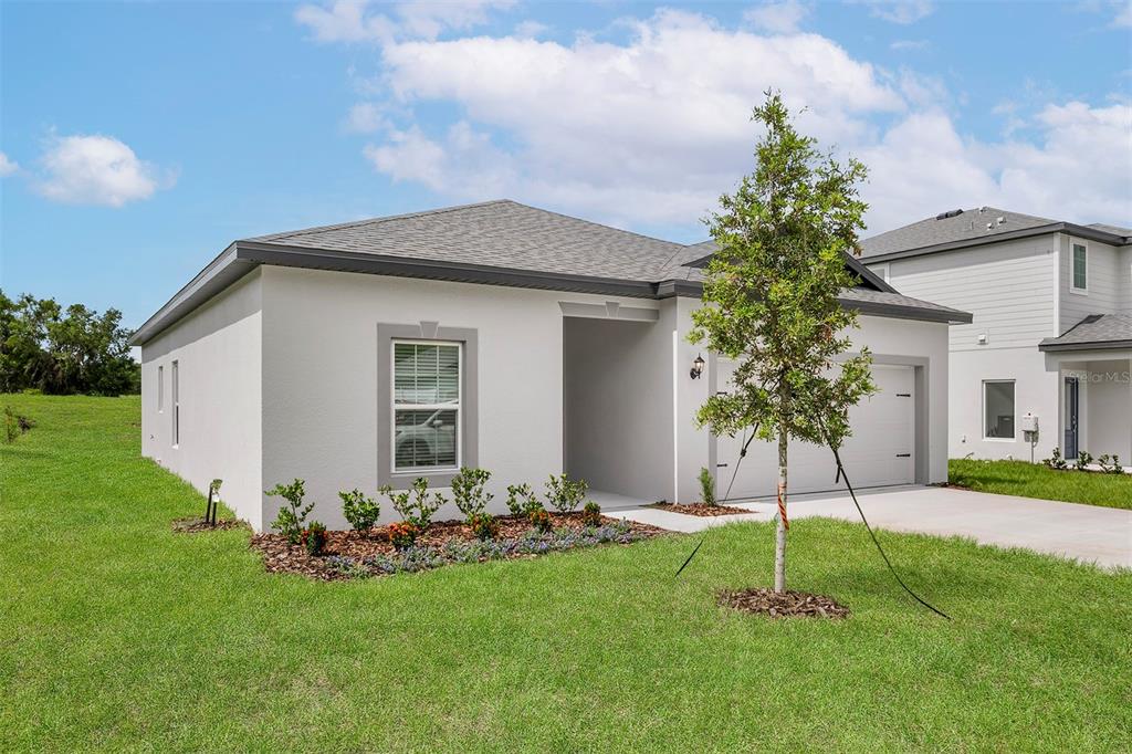 A single-story house with a white stucco exterior, a gray roof, and a front lawn — 13352 TULA LOOP, ASTATULA, FL