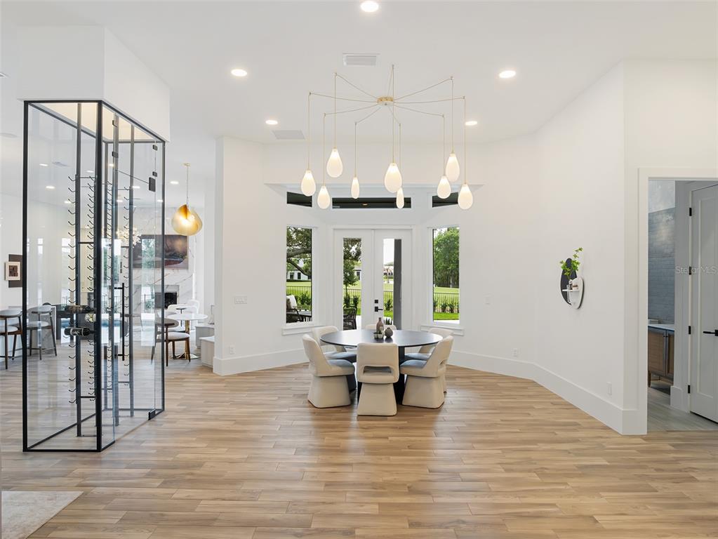 A dining area features a round table, modern chandelier, and a glass-enclosed wine cellar — 5138 FAIRWAY OAKS DR, WINDERMERE, FL