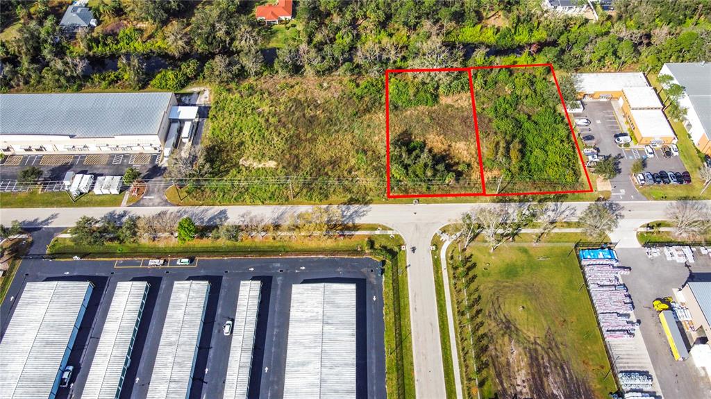 An aerial view shows two adjacent vacant lots outlined in red next to commercial buildings — 2725 COMMERCE PARKWAY, NORTH PORT, FL
