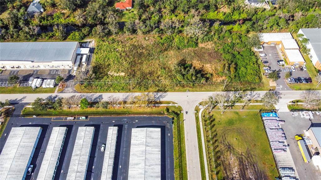 An aerial view shows a vacant, rectangular lot situated between two commercial warehouse properties — 2725 COMMERCE PARKWAY, NORTH PORT, FL