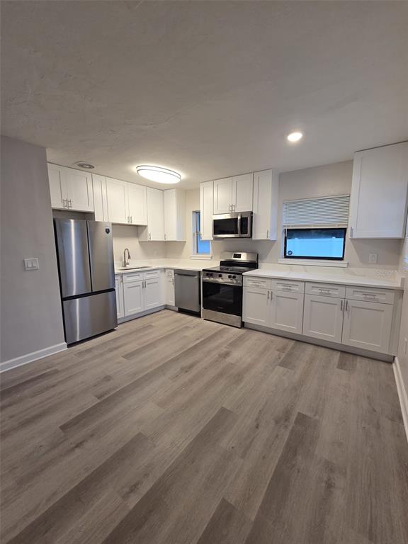 A kitchen with white cabinets, stainless steel appliances, and light wood-look flooring — 327 BARBARA CIRCLE, BELLEAIR, FL