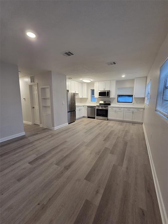 A kitchen with white cabinets, stainless steel appliances, and light wood-look flooring — 327 BARBARA CIRCLE, BELLEAIR, FL
