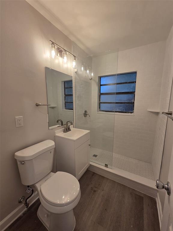A bathroom features a white vanity, a toilet, and a walk-in shower with subway tile — 327 BARBARA CIRCLE, BELLEAIR, FL