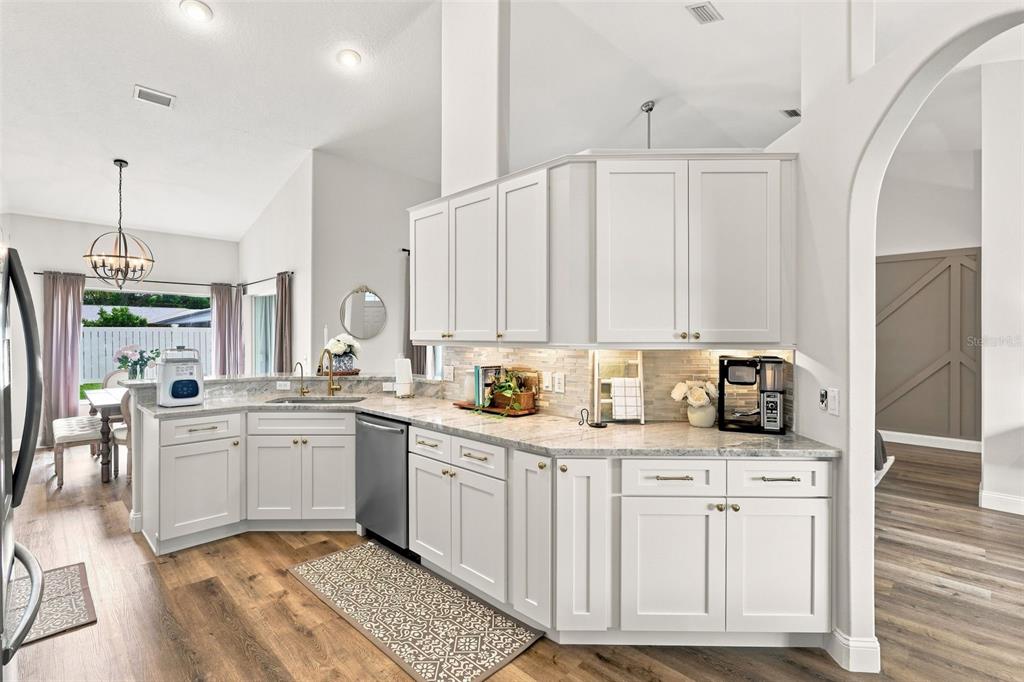 A kitchen features white cabinetry, light granite countertops, stainless steel appliances, and wood-look flooring — 96 PARKVIEW DRIVE, PALM COAST, FL
