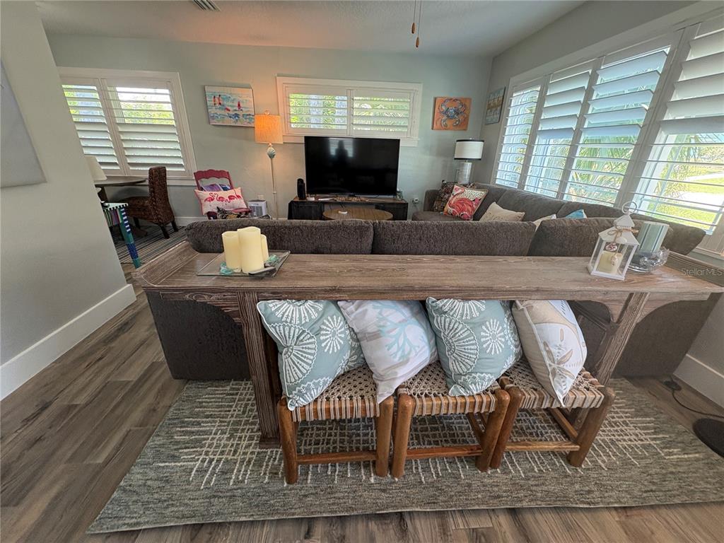 A living room features a sofa, a console table with stools, and plantation shutters — 1517 S CENTRAL AVENUE, FLAGLER BEACH, FL